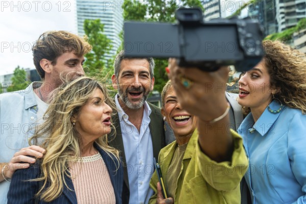 Group of diverse business professionals and colleagues enjoying a moment together, laughing and smiling while taking a collaborative selfie outdoors in an urban environment