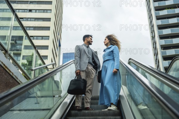 Two business professionals ascending an escalator, engaging in a conversation with modern architecture and city buildings forming the background, symbolizing upward mobility and career progression