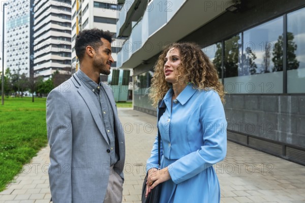 Diverse business professionals discussing work on a modern city street, representing teamwork, communication, and urban entrepreneurship in a contemporary corporate environment