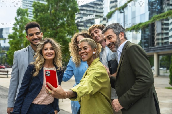 Diverse group of smiling business professionals and colleagues posing together for a group selfie outdoors in an urban city setting with modern buildings