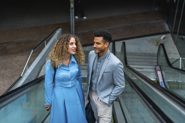 Two diverse business colleagues engaging in conversation while traveling on an escalator, representing urban commuting, networking, professionalism, and modern city life