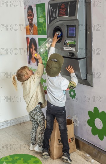Two children, 5 and 7 years old, earn pocket money by recycling cans in a recycling machine in Ystad, Skåne County, Sweden, Scandinavia