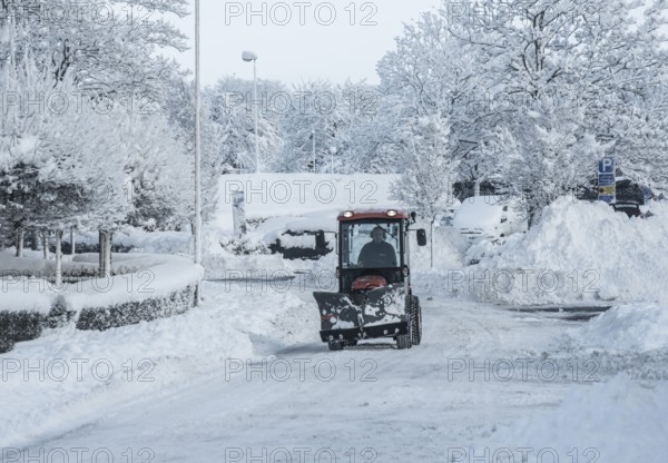 A small tractor with snow plow on snow-covered street in Ystad, Skåne County, Sweden, Scandinavia