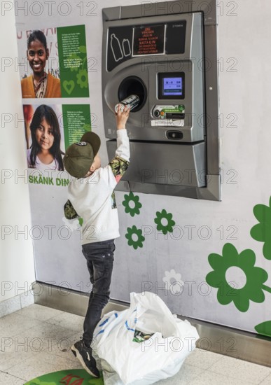 Boy, 7 years old, earns pocket money by recycling cans in recycling machine in Ystad, Skåne County, Sweden, Scandinavia