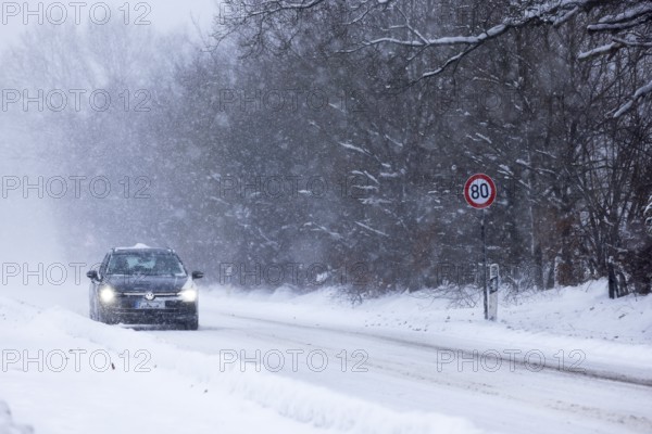 Road traffic in winter, car driving on heavily icy road covered with snow and black ice in a snowstorm, risk of accident, Schleswig-Holstein, Germany
