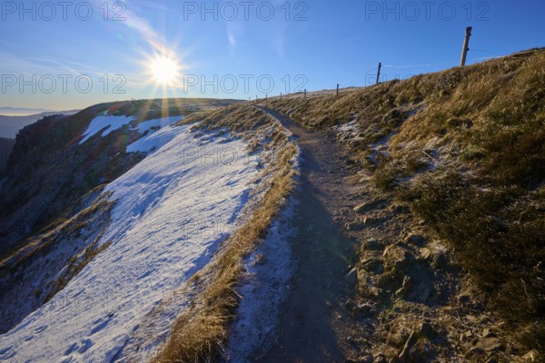 Path along a snowy mountainside at sunrise with frosty atmosphere, winter, Route de Cretes, Hohneck, La Bresse, Vosges, France