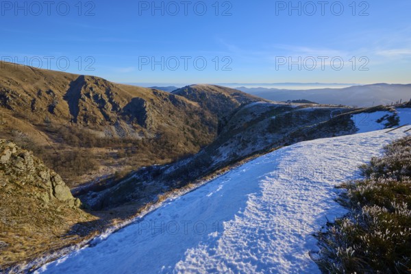 Snowy mountain slopes under blue sky revealing a vast valley and mountains, winter, Route de Cretes, Hohneck, La Bresse, Vosges, France