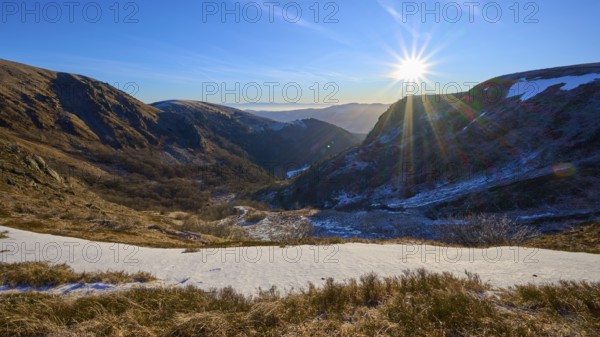 Snowy valley at sunrise with clear blue sky and bright sunbeams, winter, Route de Cretes, Hohneck, La Bresse, Vosges, France