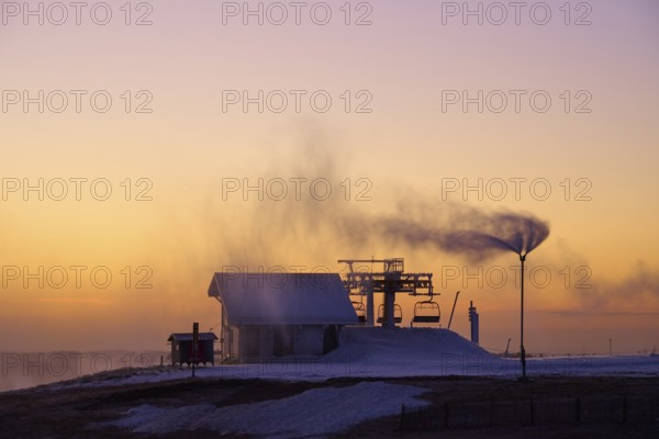 Snow cannons produce fog in orange sunset, winter, Route de Cretes, Hohneck, La Bresse, Vosges, France