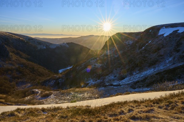 Sunrise in a snowy mountain valley with rays of light and a clear view, morning, winter, Hohneck, La Bresse, Vosges, France