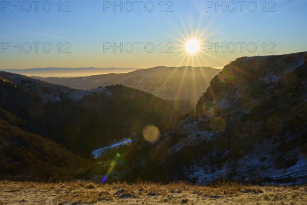 Sunrise over a snowy mountain valley with clear sky and rays of light, morning, winter, Hohneck, La Bresse, Vosges, France