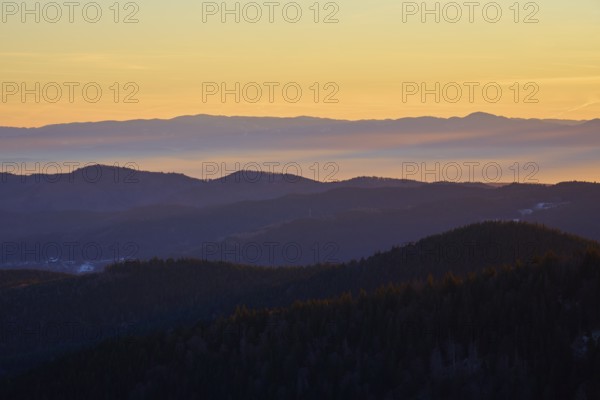 Mountains in silhouette at sunrise in warm shades of orange and yellow, view, Rhine Valley, Hohneck, La Bresse, Vosges, France