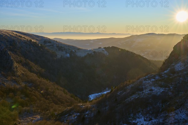 View of a snowy valley under clear sky with sunlight and light fog, morning, winter, Hohneck, La Bresse, Vosges, France