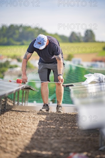 A worker on a construction site measures something while installing solar systems, new park and ride parking garage Calw Heumaden at the new Hermann Hessebahn, Calw, Germany