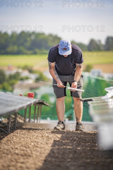 A man on a construction site measuring for the installation of solar systems, new Park and Ride parking garage Calw Heumaden on the new Hermann Hessebahn, Calw, Germany