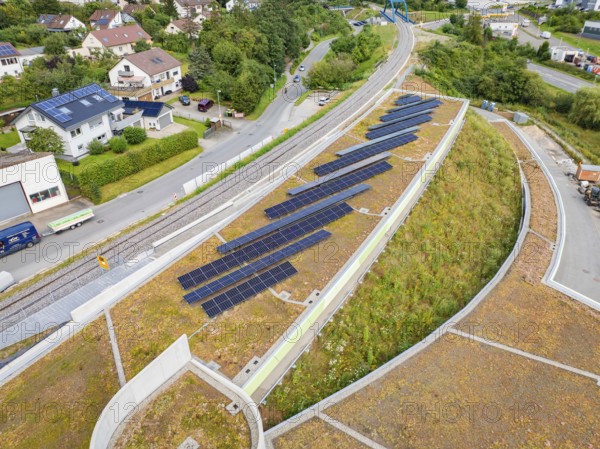Solar panels on a green hill next to a road and railway line in a residential area, new park and ride parking garage Calw Heumaden on the new Hermann Hessebahn, Calw, Germany