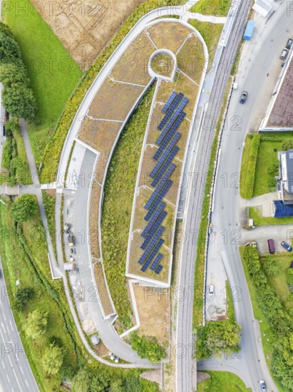 Aerial view of a building with solar panel, surrounded by roads and green vegetation, new park and ride parking garage Calw Heumaden on the new Hermann Hessebahn, Calw, Germany