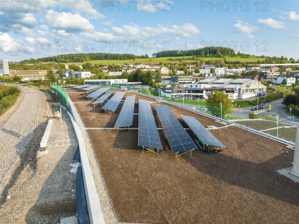 Solar systems on a flat roof with wide green areas and buildings in the background, new Park and Ride Calw Heumaden car park on the new Hermann Hessebahn, Calw, Germany