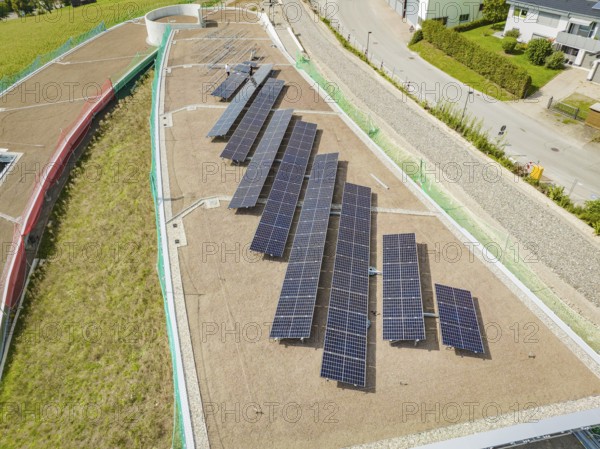 Solar panels on a flat roof next to a street and buildings, surrounded by green vegetation, new park and ride parking garage Calw Heumaden on the new Hermann Hessebahn, Calw, Germany