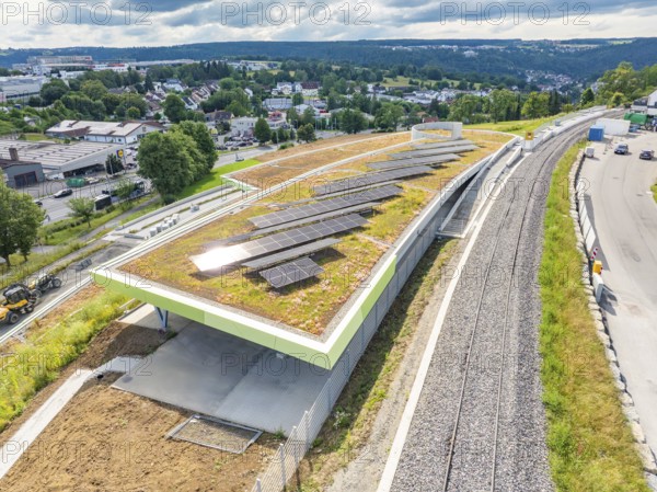 Building with solar system on green roof next to railroad tracks in a cloudy landscape, new park and ride parking garage Calw Heumaden on the new Hermann Hessebahn, Calw, Germany