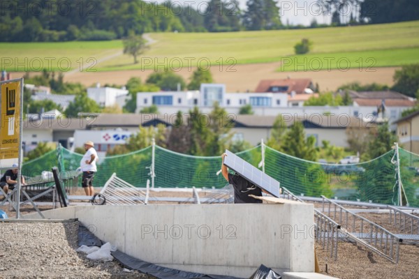 A worker on a construction site assembling solar panels in a rural area, new park and ride parking garage Calw Heumaden on the new Hermann Hessebahn, Calw, Germany