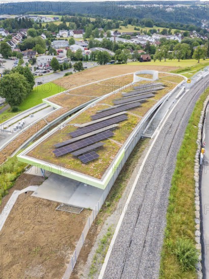 Solar panels on a covered building next to a railway line, surrounded by countryside, new park and ride parking garage Calw Heumaden on the new Hermann Hessebahn, Calw, Germany