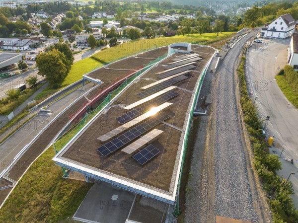 A roof with solar panels in a lively landscape with a view of a city, new park and ride parking garage Calw Heumaden on the new Hermann Hessebahn, Calw, Germany