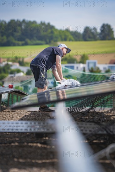 Workers installing a solar system on a roof with a view of the surrounding area, new park and ride parking garage Calw Heumaden on the new Hermann Hessebahn, Calw, Germany