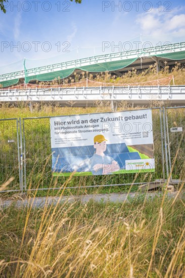 Construction site with advertising for photovoltaic systems for regional power generation under blue skies, new Park and Ride Calw Heumaden car park on the new Hermann Hessebahn, Calw, Germany