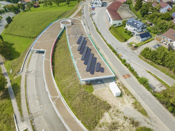Large solar panel system on roof surrounded by rural village and greenery, new park and ride parking garage Calw Heumaden on the new Hermann Hessebahn, Calw, Germany