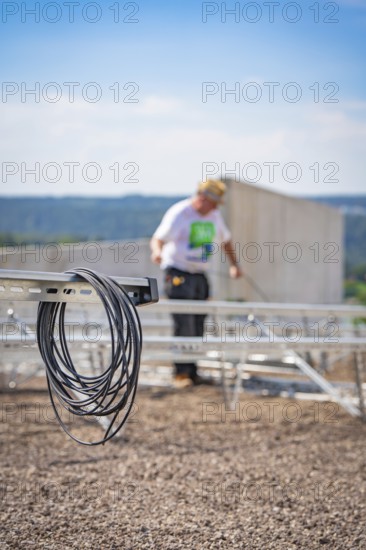 Cable against a blurred background showing workers installing a solar system, new park and ride parking garage Calw Heumaden at the new Hermann Hessebahn, Calw, Germany
