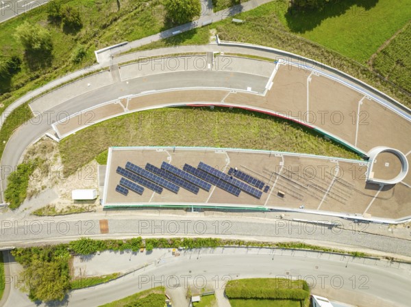 Aerial view of solar panel system on roof next to road and green area, new park and ride parking garage Calw Heumaden on the new Hermann Hessebahn, Calw, Germany