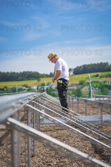 A construction worker stands on scaffolding in a rural area under blue skies, new park and ride parking garage Calw Heumaden on the new Hermann Hessebahn, Calw, Germany