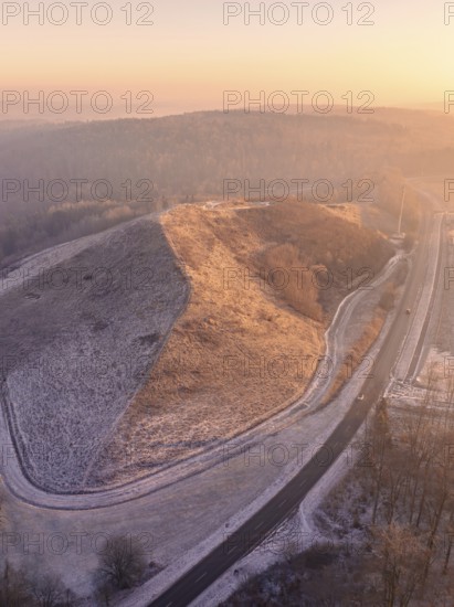 Snowy hill in sunset light with surrounding roads, old deposit, construction site for PV open space plant, Lindenrain, Calw, Germany