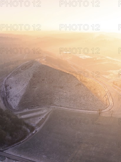 View of a snow-covered hill in fog and warm light, old deposit, construction site for PV open space plant, Lindenrain, Calw, Germany