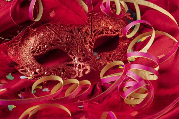 Red mask with confetti, feathers and colorful streamers, carnival