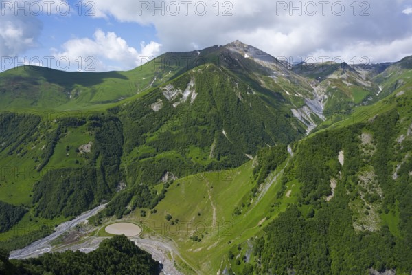 Green mountain landscape with blue sky and clouds, natural natural beauty, mountain landscape between Gudauri and Cross Pass, Mount Sherkhota, Mtskheta-Mtianeti region, Georgian Military Highway, High Caucasus, Georgia