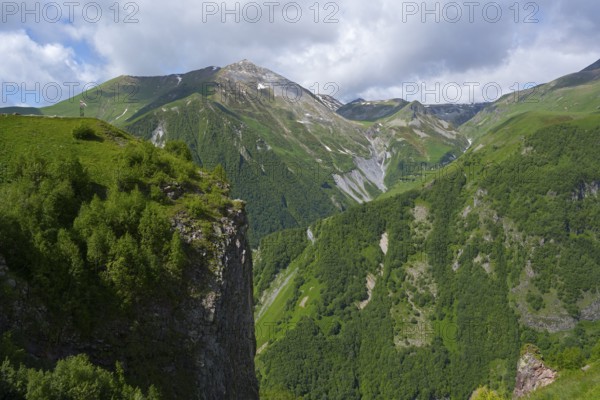 Green mountains under blue sky with clouds, peaceful summer day in nature, mountainous landscape between Gudauri and Cross Pass, Mount Sherkhota, Mtskheta-Mtianeti region, Georgian Military Highway, High Caucasus, Georgia
