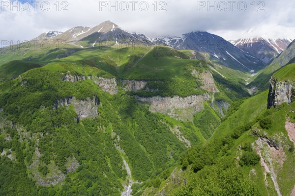 Green mountains with deep gorges under cloudy sky, mountainous landscape between Gudauri and Cross Pass, Mount Sherkhota, Mtskheta-Mtianeti region, Georgian Military Highway, High Caucasus, Georgia