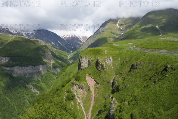Green mountain landscape with visible road and gorges, cloudy weather, mountainous landscape between Gudauri and Cross Pass, Mount Sherkhota, Mtskheta-Mtianeti region, Georgian Military Highway, High Caucasus, Georgia