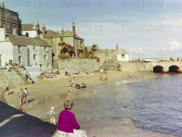 People in swimsuits on sandy beach at The Wharf, St Ives, Cornwall, England, UK 1960s