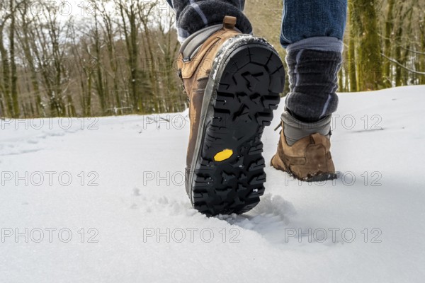 Hiker stepping in deep snow with rugged sole hiking boots, showcasing outdoor trekking, adventure, and exploration during a cold winter journey through a natural landscape