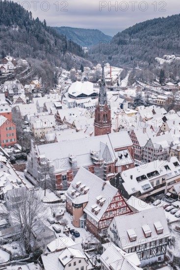 Snowy old town district with church and half-timbered houses in a mountain backdrop, Calw, Black Forest, Germany