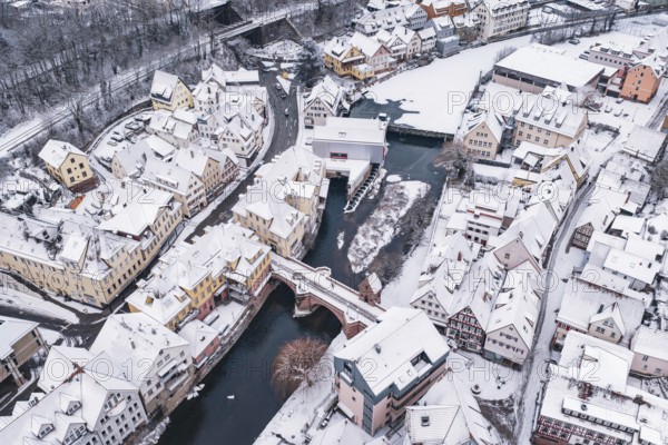Snowy town crossed by a river with bridge and traditional buildings, Calw, Black Forest, Germany