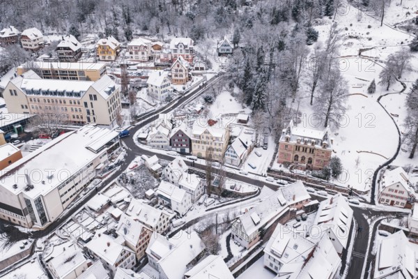 Snowy town with traditional houses and buildings nestled in a hilly winter landscape, Calw, Black Forest, Germany