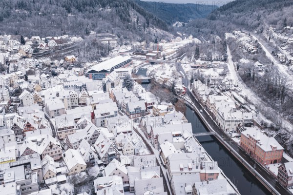 City in winter with snowy buildings, river and adjacent hills and bridge, Calw, Black Forest, Germany
