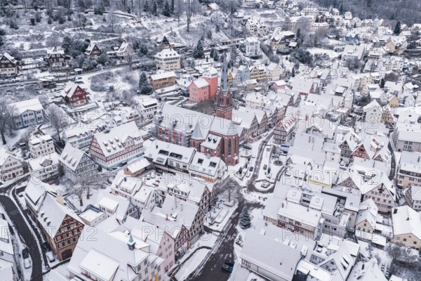 Church buildings surrounded by a snowy town with traditional architecture in winter, Calw, Black Forest, Germany