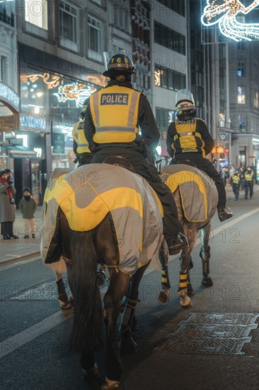 Mounted police at night on a street with festive lights, London, England, Great Britain
