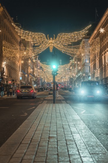 Festively illuminated street with Christmas decorations and cars at night, London, England, Great Britain