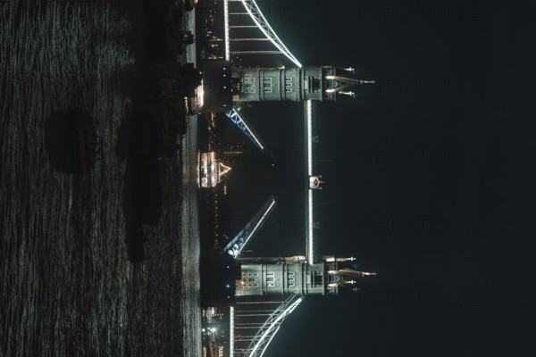 Illuminated Tower Bridge stretches across the river at night, London, England, Great Britain